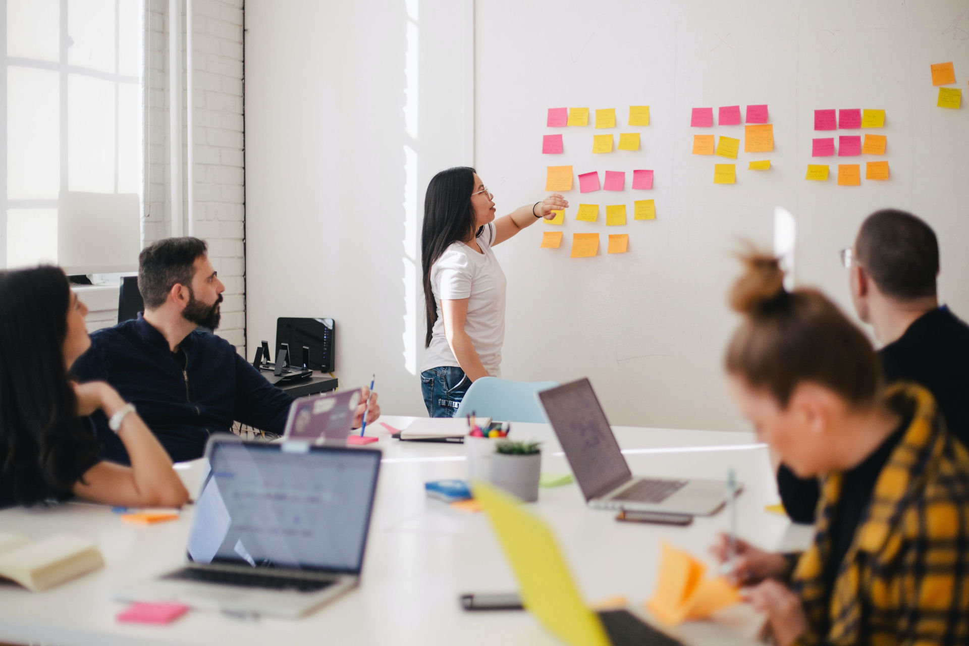 Une personne en formation présente des post-its à un groupe autour d'une table.